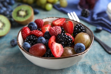 Photo of Fresh tasty fruit salad on blue wooden table, closeup