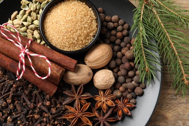 Photo of Dishware with different spices and fir branches on table, top view