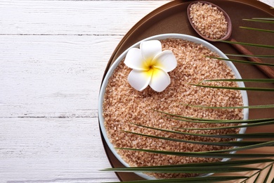 Photo of Flat lay composition with brown sea salt on white wooden background, space for text. Spa treatment