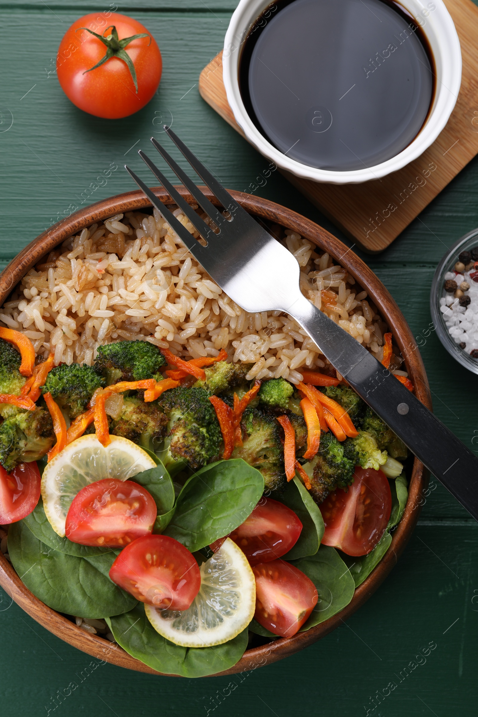 Photo of Tasty fried rice with vegetables served on green wooden table, flat lay