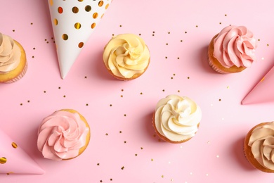 Photo of Flat lay composition with delicious birthday cupcakes on color background