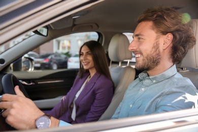 Happy young man and woman in modern car