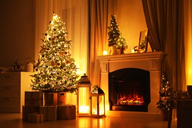 Stylish living room interior with beautiful fireplace, Christmas tree and other decorations at night