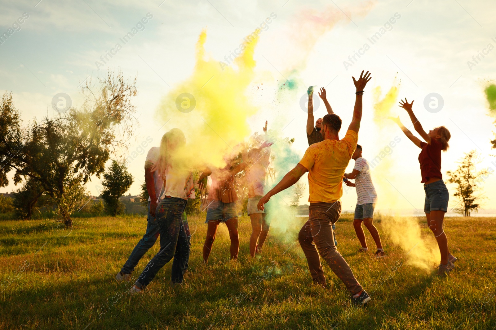 Photo of Happy friends having fun with colorful powder dyes outdoors. Holi festival celebration