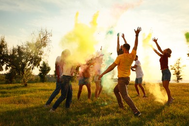 Happy friends having fun with colorful powder dyes outdoors. Holi festival celebration