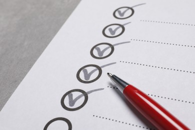 Paper sheet with checkboxes and pen on light grey table, closeup. Checklist