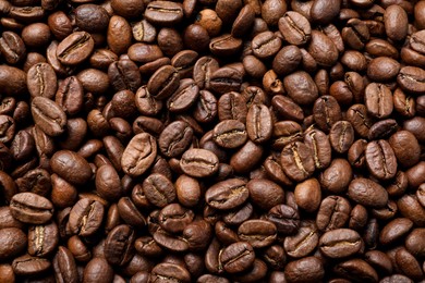 Photo of Pile of roasted coffee beans as background, top view