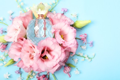 Luxury perfume and floral decor on light blue background, flat lay