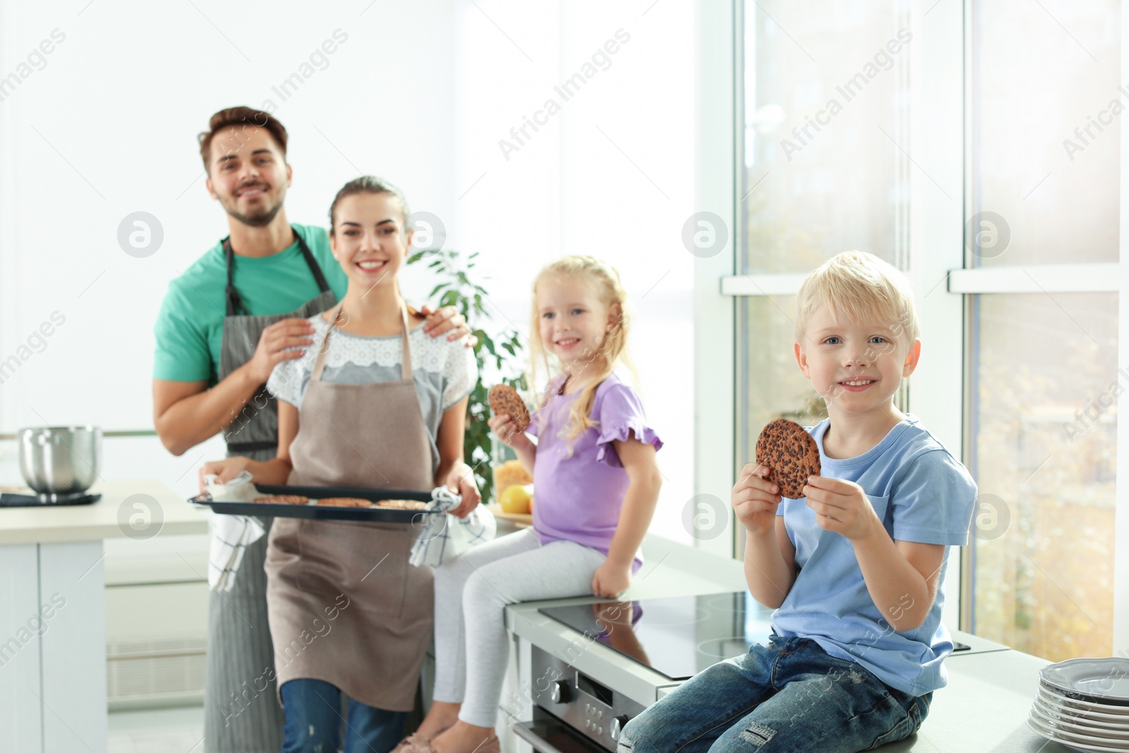 Photo of Happy boy and his family eating homemade oven baked cookies in kitchen
