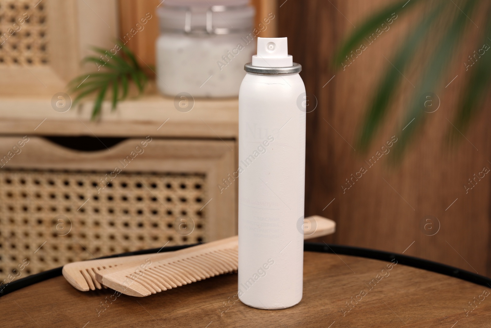 Photo of Dry shampoo spray and combs on wooden table in bathroom