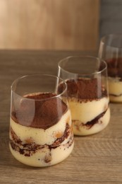 Photo of Delicious tiramisu in glasses on wooden table