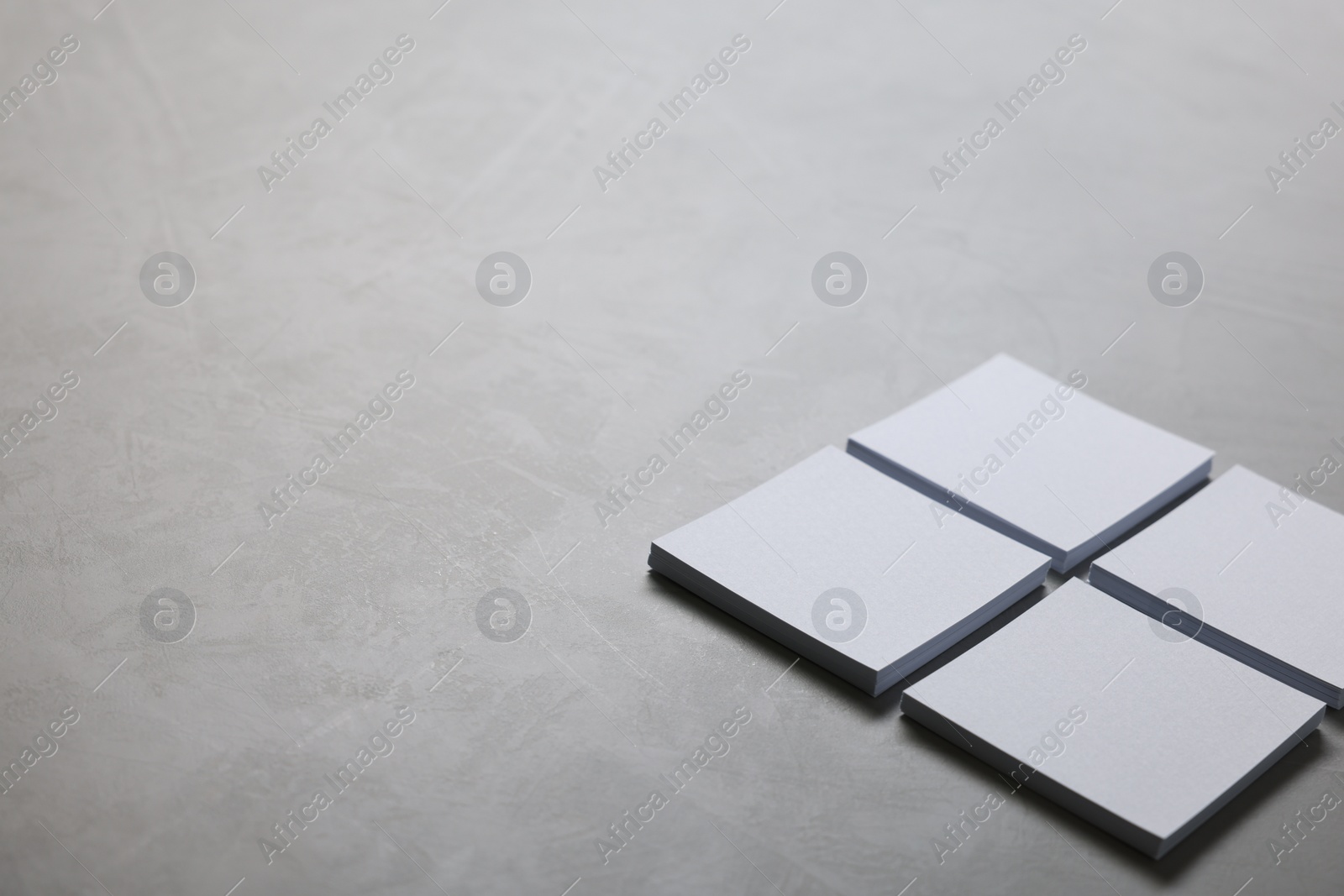 Photo of Blank paper sheets on grey textured table, closeup. Mockup for design