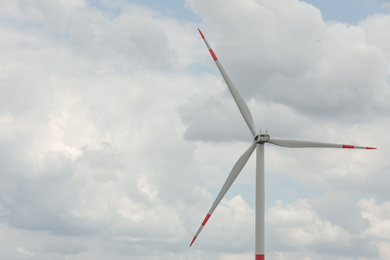 Photo of Modern wind turbine against cloudy sky, closeup. Alternative energy source