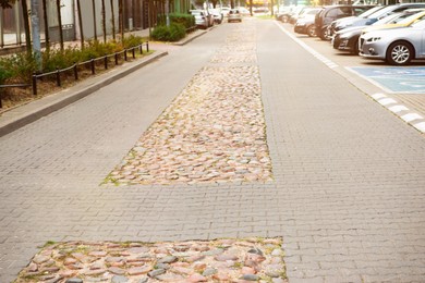Photo of Sidewalk path near cars on city street. Footpath covering