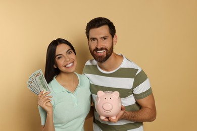 Photo of Happy couple with money and ceramic piggy bank on beige background