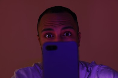 Photo of Man using smartphone at night, closeup. Internet addiction
