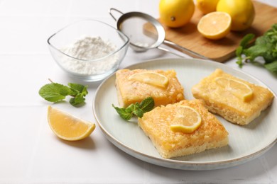 Photo of Tasty lemon bars and mint on white table
