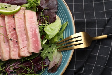 Pieces of delicious tuna steak with salad on checkered fabric, top view