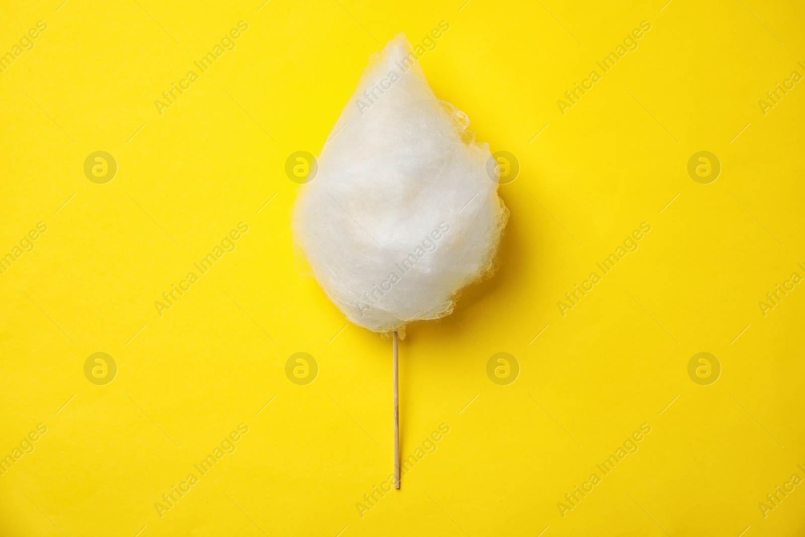 Photo of Stick with yummy cotton candy on color background, top view