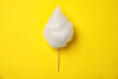 Photo of Stick with yummy cotton candy on color background, top view