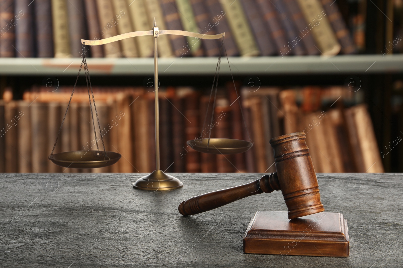 Image of Law. Judge's gavel and scale of justice on grey table against shelves with books indoors