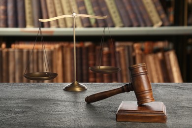 Image of Law. Judge's gavel and scale of justice on grey table against shelves with books indoors