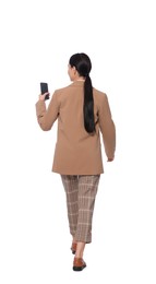 Young businesswoman using smartphone while walking on white background, back view