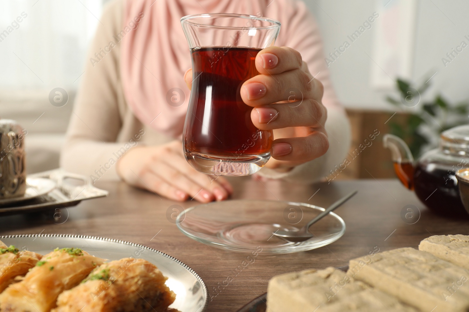 Photo of Woman with cup of delicious Turkish tea at wooden table, closeup