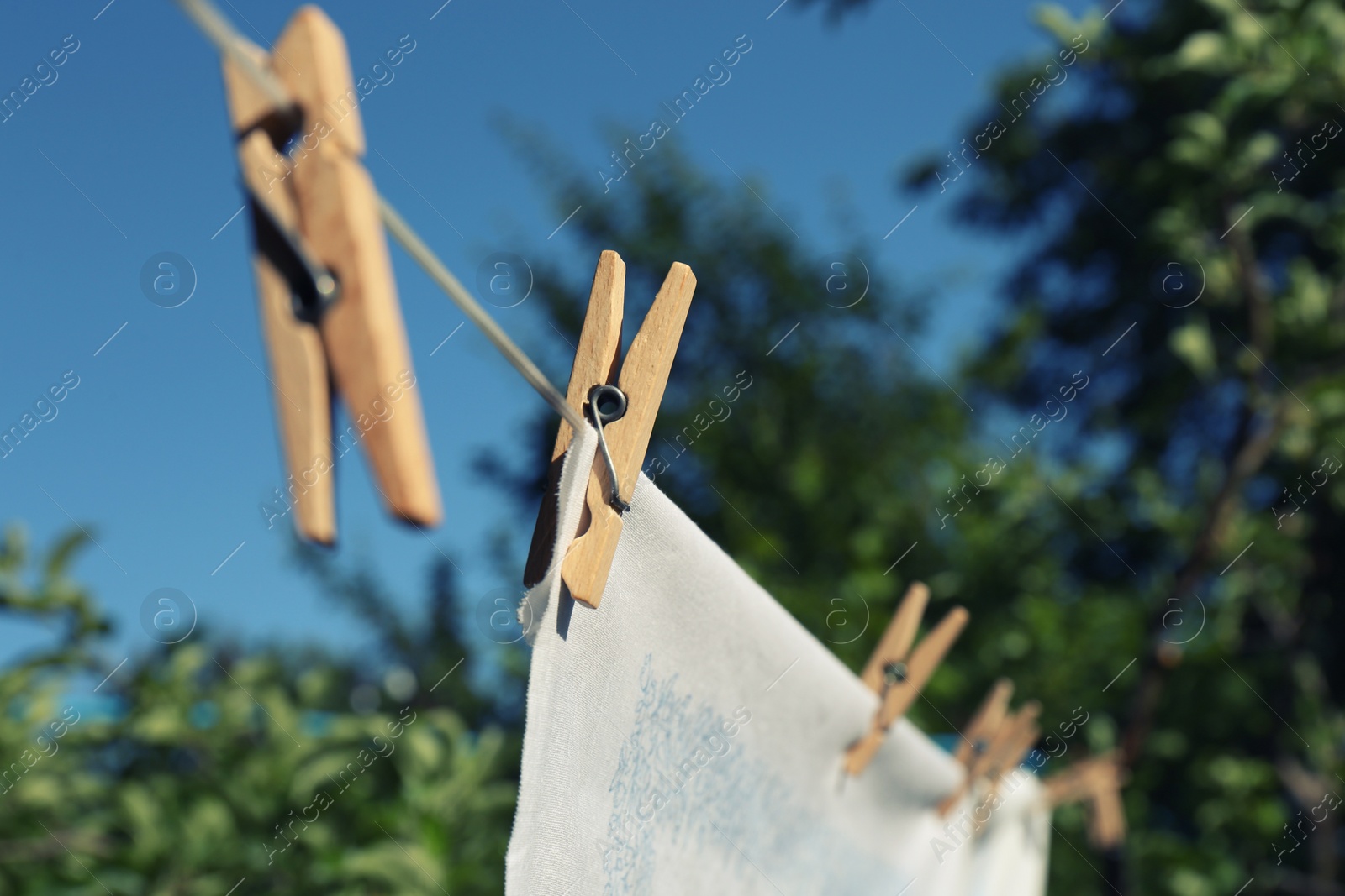 Photo of Washing line with clean laundry and clothespins outdoors, closeup