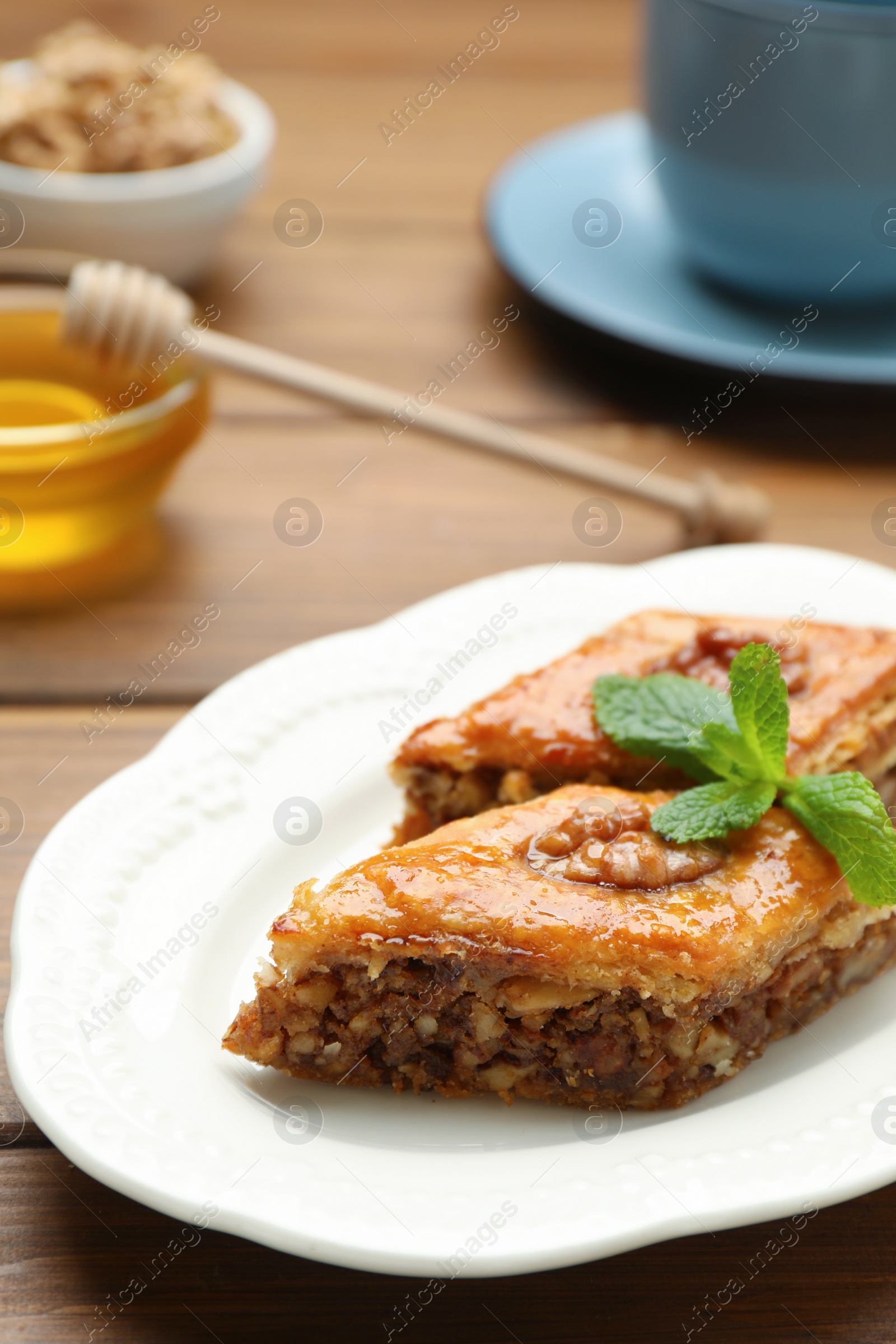 Photo of Delicious honey baklava with walnuts on wooden table, closeup