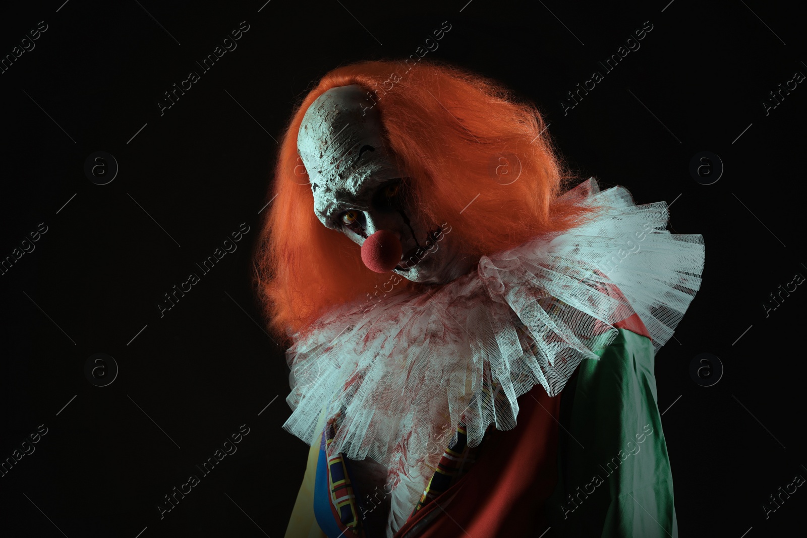 Photo of Terrifying clown on black background. Halloween party costume