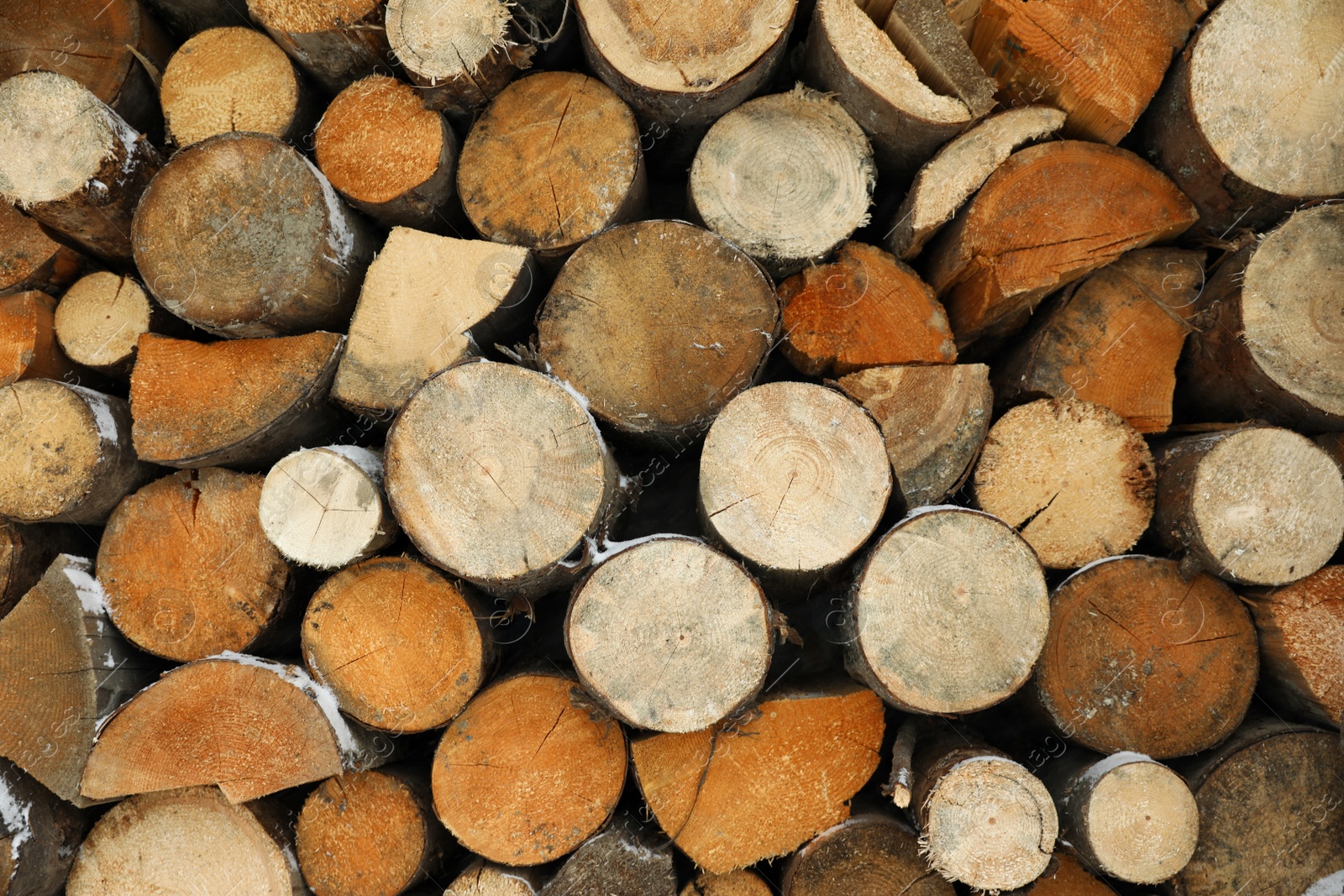 Photo of Stacked firewood with snow as background, closeup. Heating house in winter