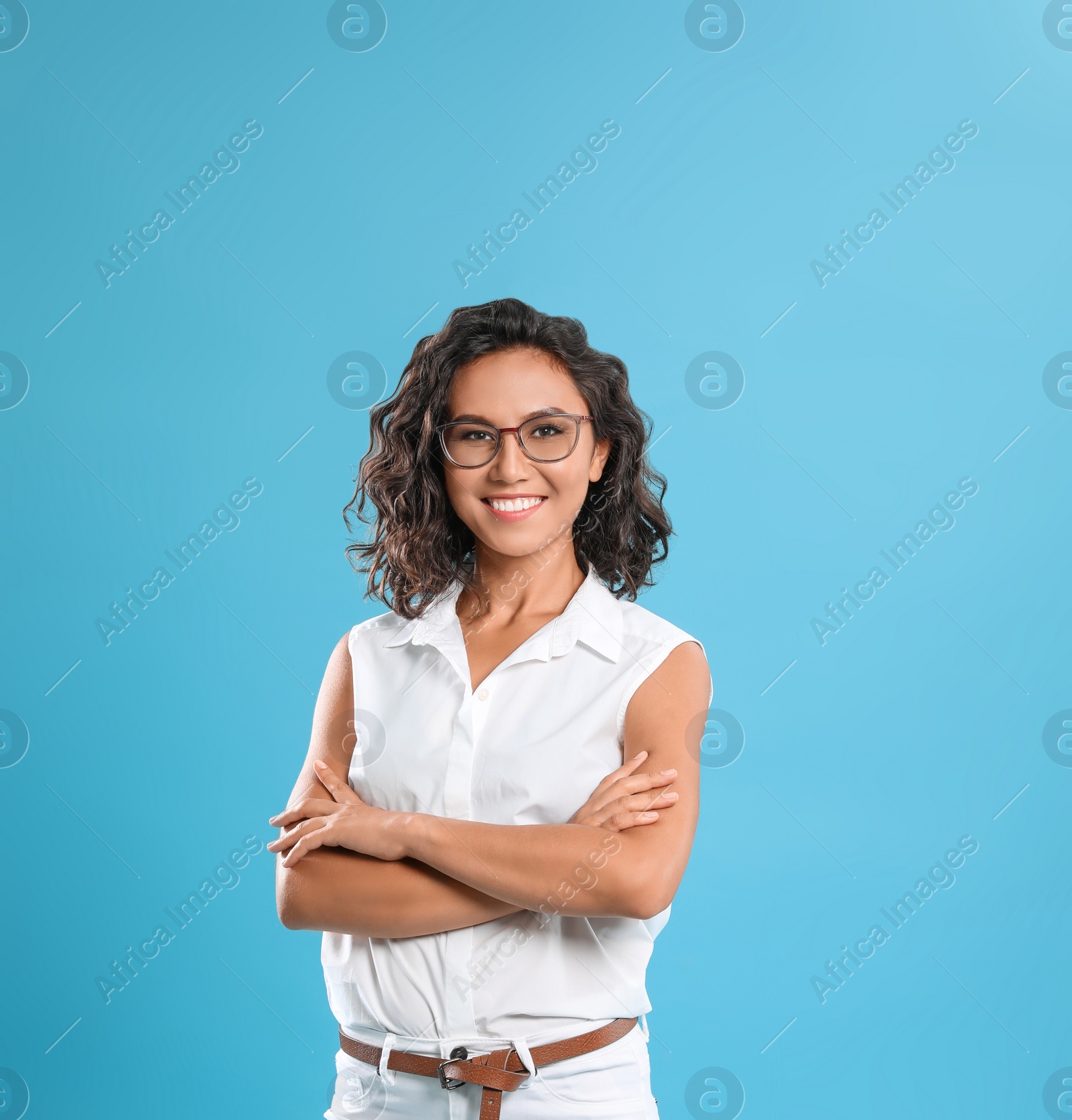 Photo of Happy young woman with crossed hands on blue background