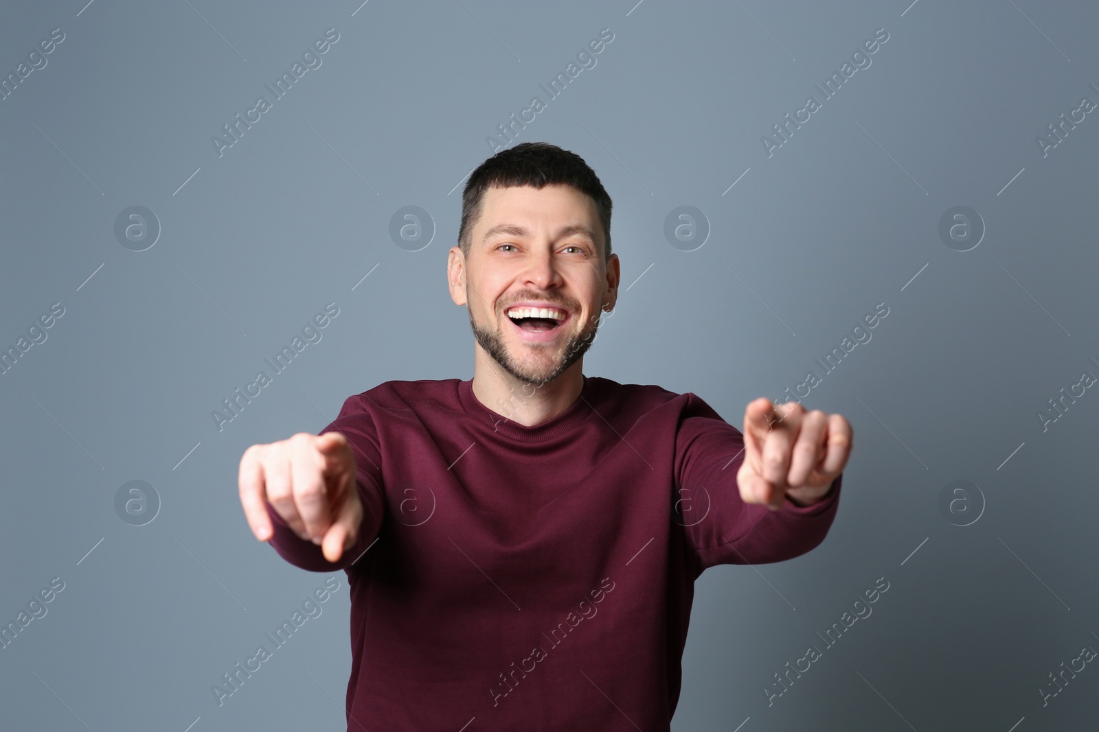 Photo of Handsome man laughing on grey background. Funny joke