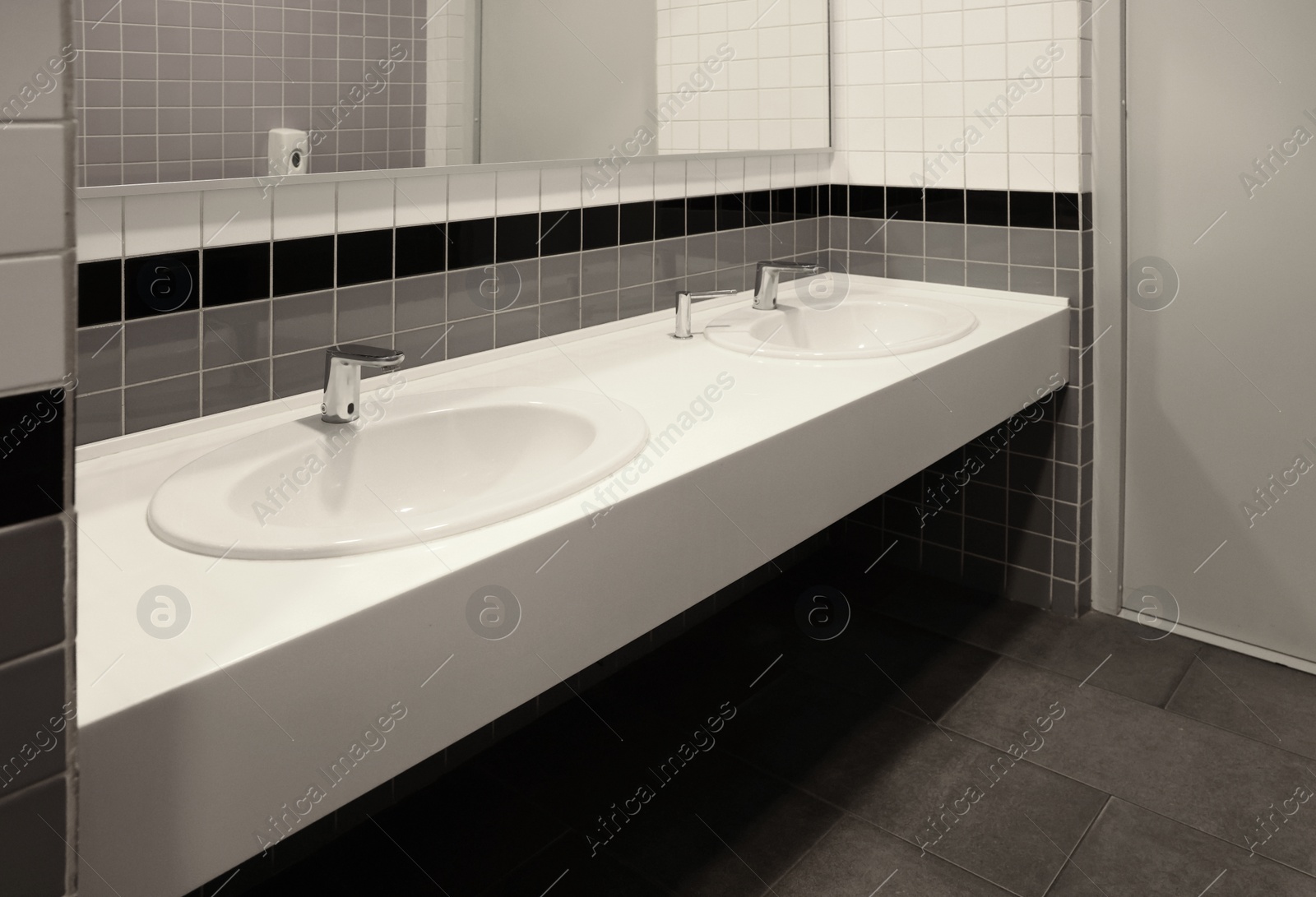 Photo of Public toilet interior with sinks and mirror