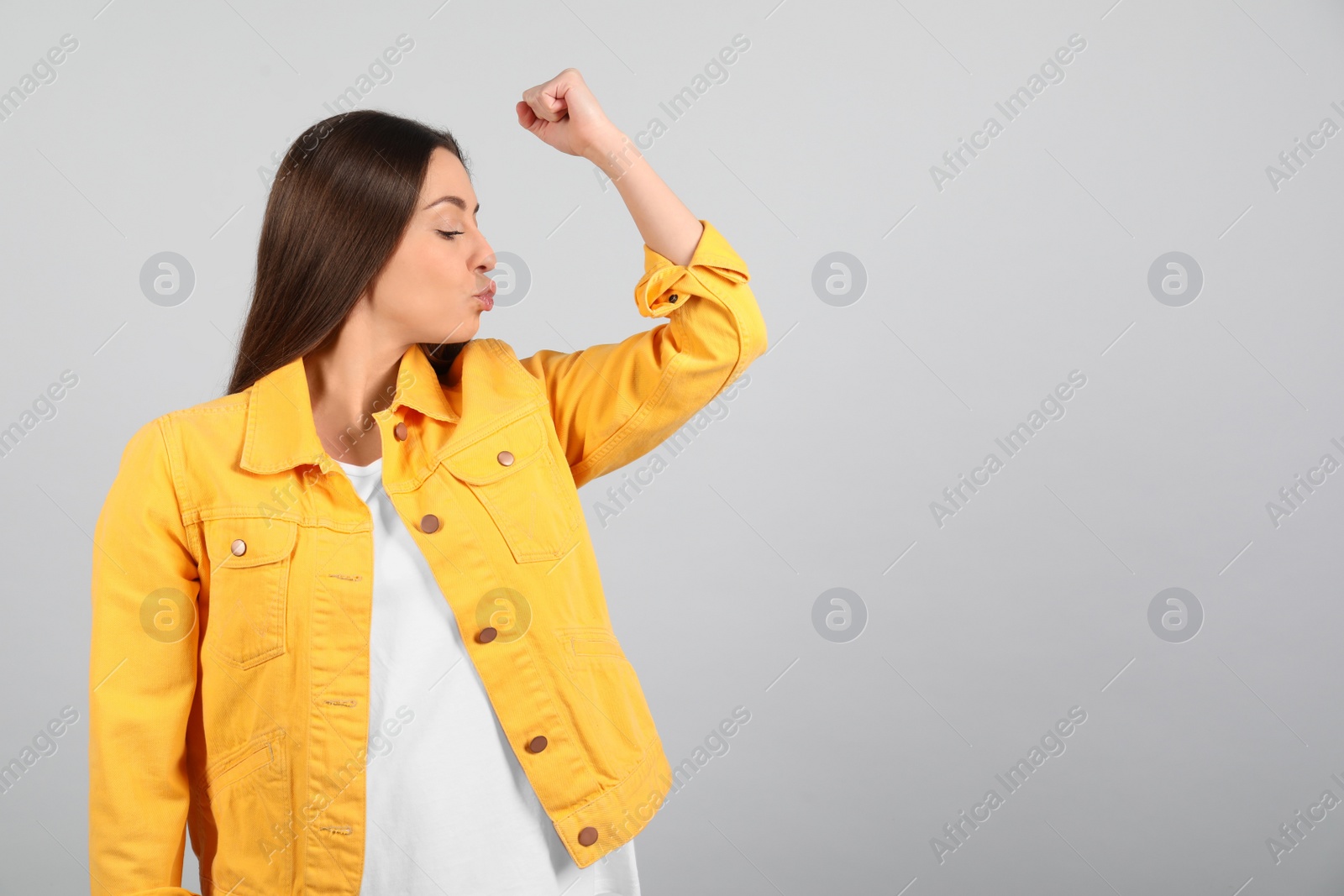 Photo of Strong woman as symbol of girl power on light grey background, space for text. 8 March concept