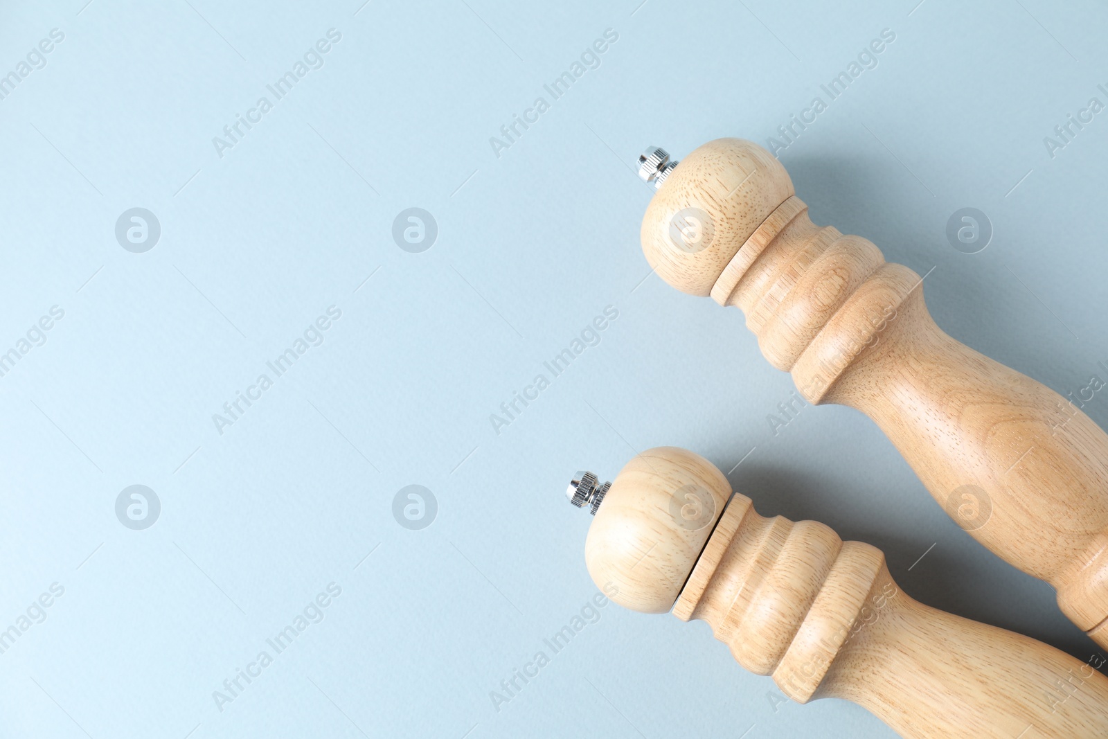 Photo of Wooden salt and pepper shakers on light background, top view. Space for text