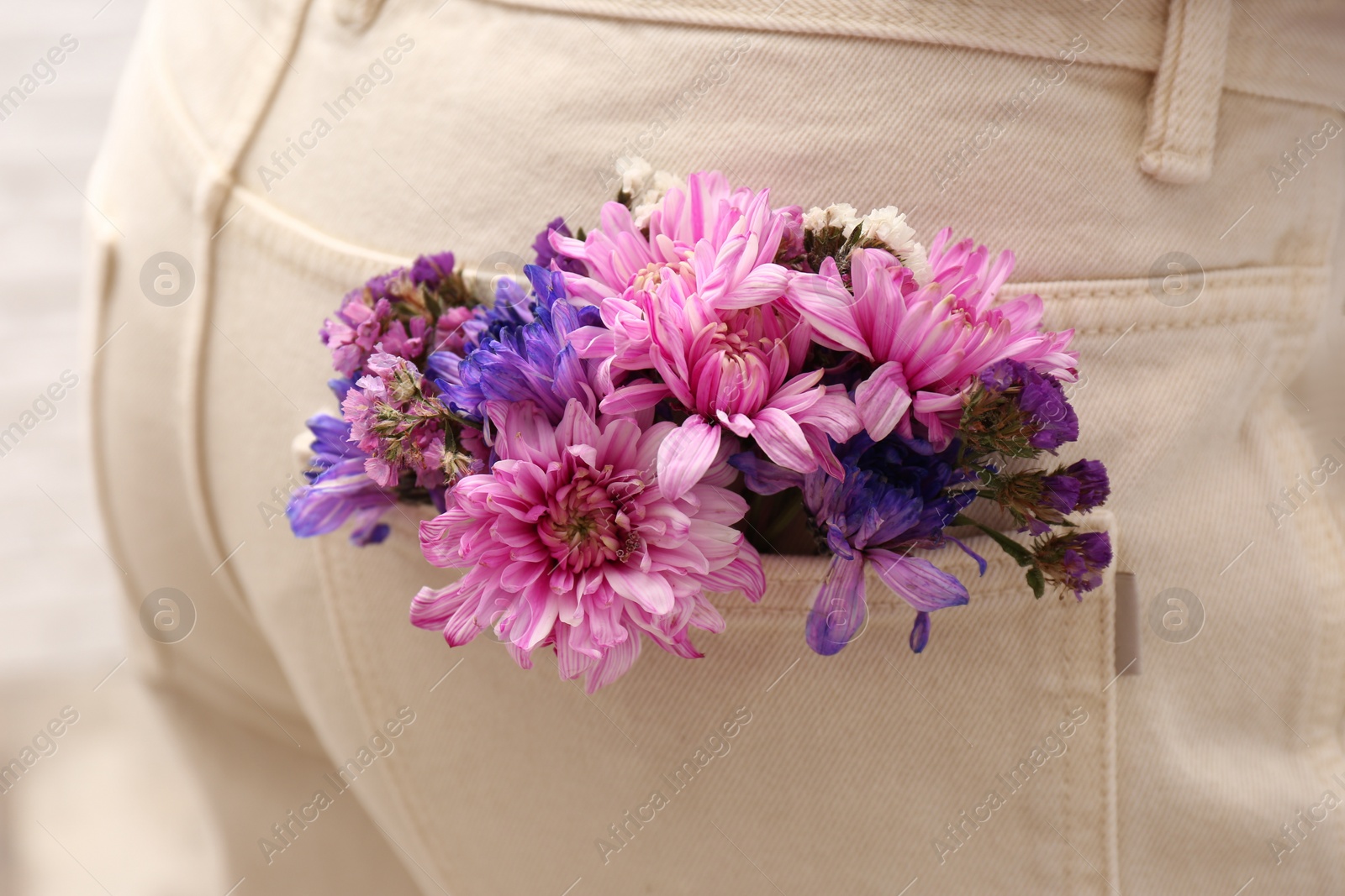 Photo of Woman wearing jeans with flowers in pocket, closeup