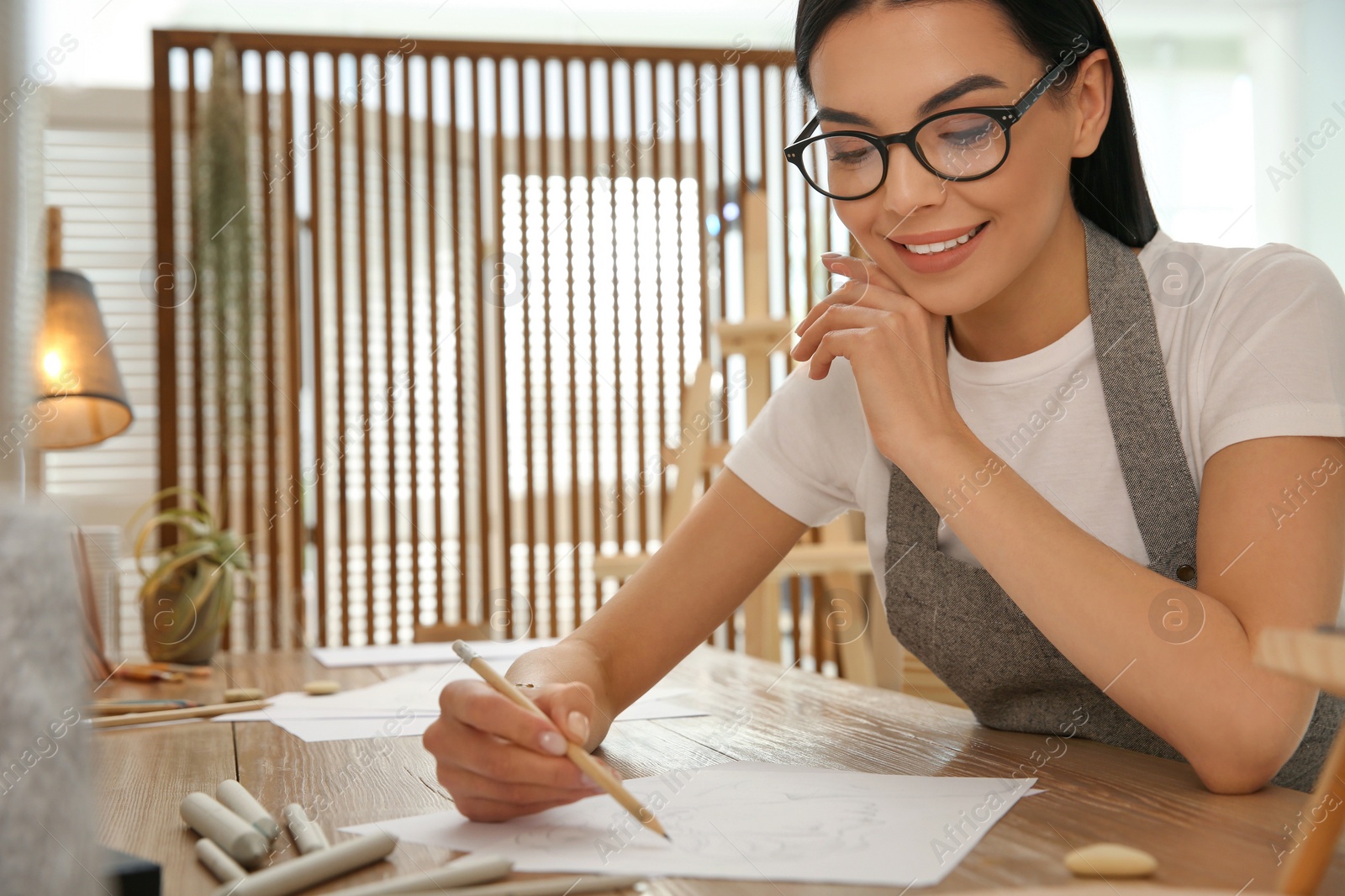 Photo of Young woman drawing at table indoors. Space for text