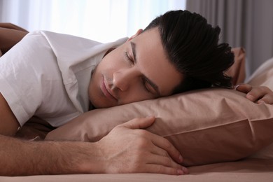 Photo of Man sleeping in comfortable bed with beige linens
