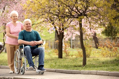 Photo of Senior man in wheelchair and woman at park on sunny day