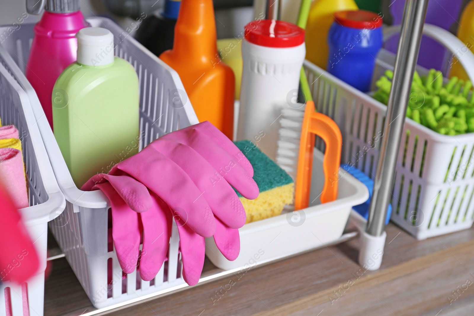 Photo of Different cleaning supplies on wooden table in kitchen, closeup