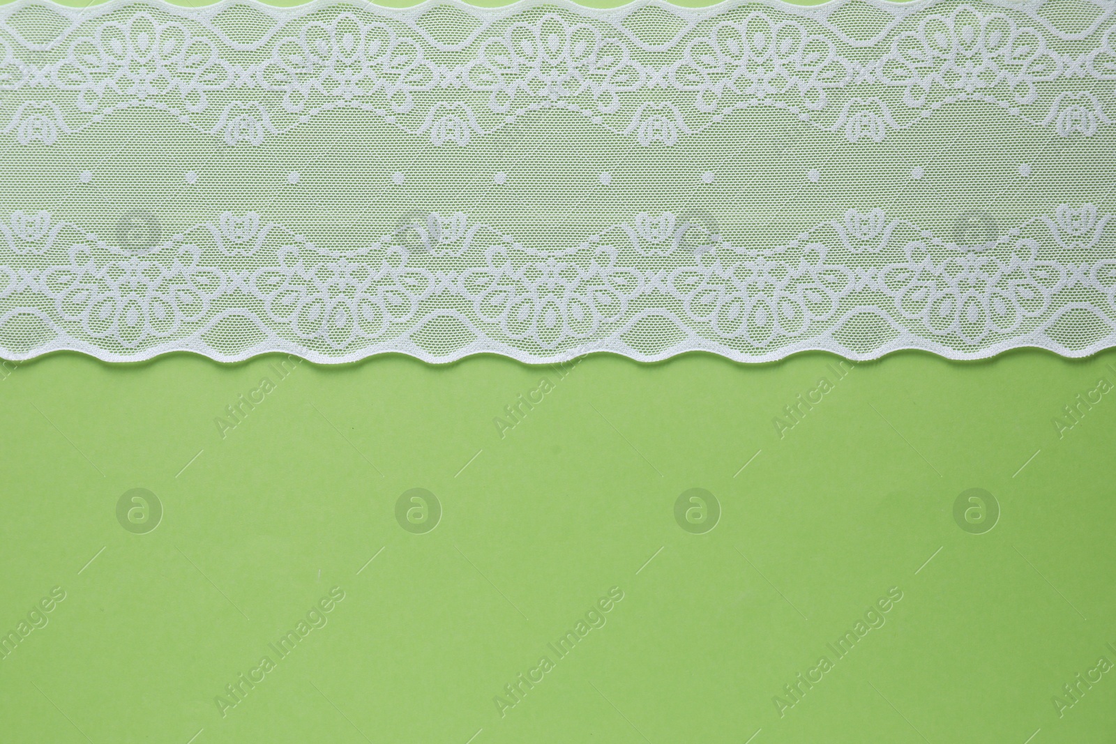 Photo of White lace on green background, top view. Space for text