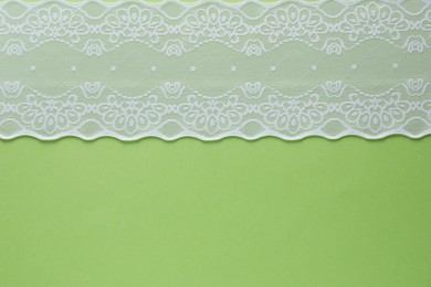 Photo of White lace on green background, top view. Space for text