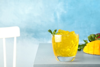 Photo of Composition with mango jelly in glass on  table against color background. Space for text