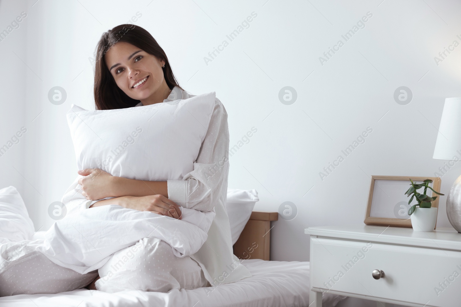 Photo of Beautiful young woman hugging pillow on bed at home