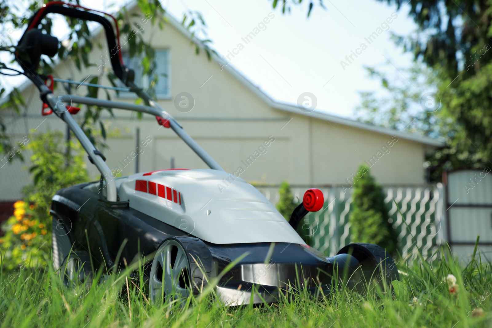 Photo of Lawn mower on green grass in garden, space for text