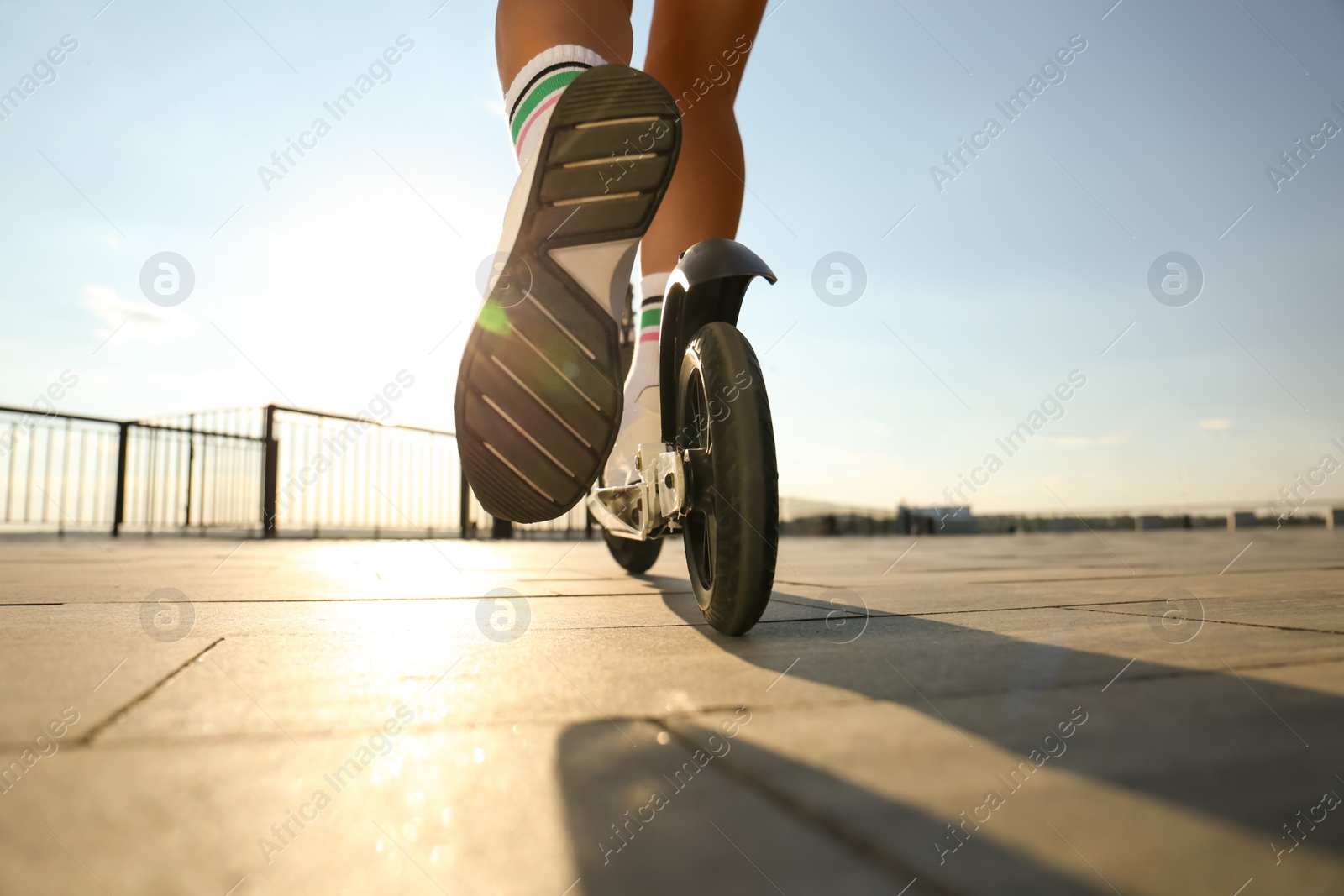 Photo of Woman riding kick scooter along city street, closeup