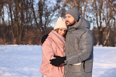 Photo of Happy couple hugging in sunny snowy park. Space for text