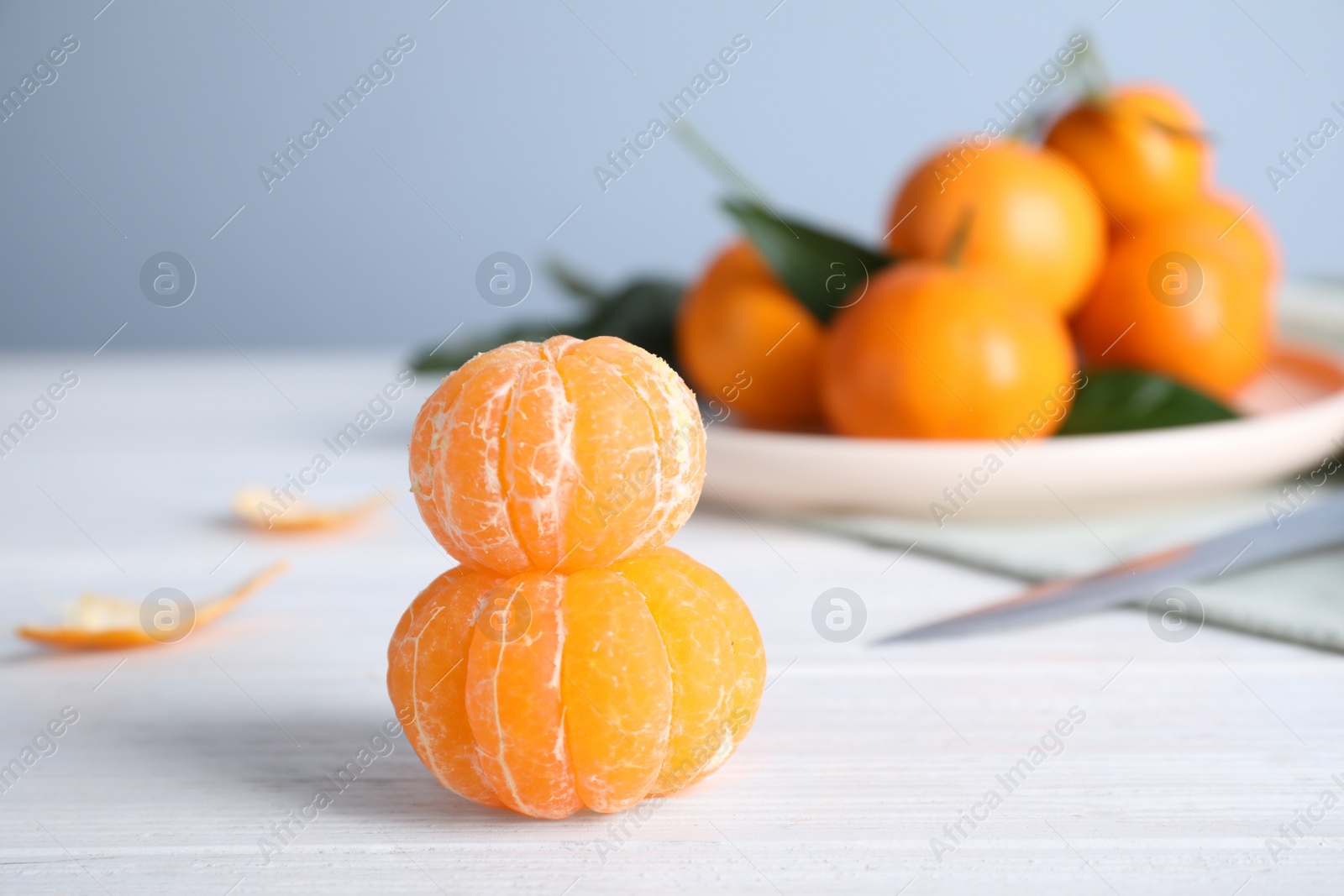 Photo of Peeled ripe tangerines on white wooden table. Space for text